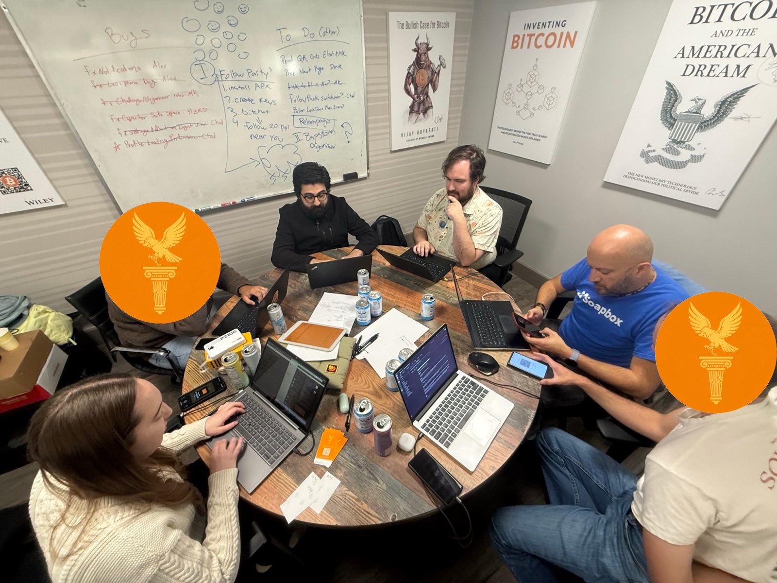 The full Agora team working around a conference table with laptops, whiteboards covered in ideas behind them